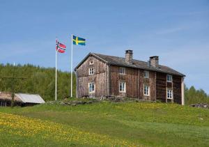 an old house with two flags on top of a field at Hotell Klimpfjäll in Klimpfjäll