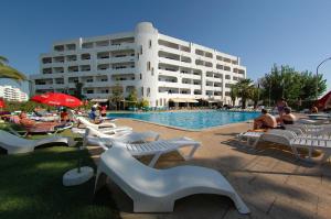 a large building with a pool with people sitting around it at Apartamentos Turisticos Silchoro in Albufeira