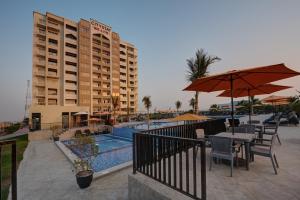 a patio area with tables, chairs and umbrellas at City Stay Beach Hotel Apartments - Marjan Island in Ras al Khaimah