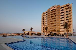 a hotel with a swimming pool in front of a building at City Stay Beach Hotel Apartments - Marjan Island in Ras al Khaimah