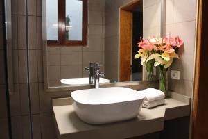 baño con lavabo blanco y jarrón de flores en Gáldar, habitación privada en la playa en Gáldar