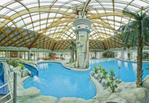 a large swimming pool in a resort with a roof at Aparthouse SUPREME with Terme Catez Swimming Pools Tickets in Čatež ob Savi