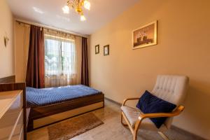 a bedroom with a bed and a chair and a window at Victus Apartamenty, Apartament Walor in Sopot