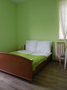 Cama en habitación con pared verde en Praski Dom en Sienno