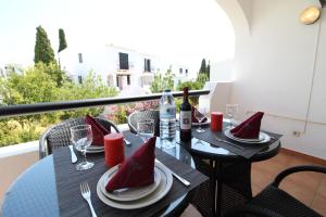 a table with wine bottles and glasses on a balcony at Apt T2 Praia São Rafael Hibiscus 18A - Albufeira, Algarve in Albufeira