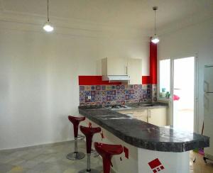 una cucina con bancone e 2 sgabelli rossi di chic appart vue sur piscine a Tangeri