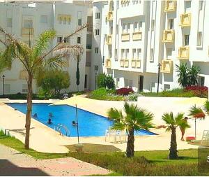 una piscina con palme di fronte a un edificio di chic appart vue sur piscine a Tangeri