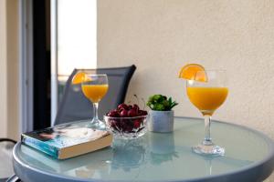 Relax Zone Apartment في ترستنو: كأسين من عصير البرتقال وكتاب على طاولة زجاجية