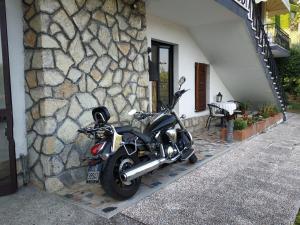 uma moto estacionada ao lado de uma parede de pedra em Villa de Ros em Salò