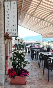 eine Terrasse mit Tischen und Stühlen und ein Schild für ein Restaurant in der Unterkunft Albergo La Torre in Radicofani