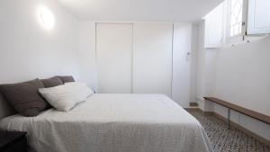 a white bedroom with a bed and a window at Casa das 3 Andorinhas in Olhão