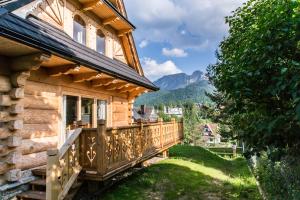 drewniany dom z balkonem z widokiem na góry w tle w obiekcie TatryTop Osada Luxury Chalets Kościelisko w mieście Kościelisko