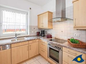 eine Küche mit Holzschränken und Spüle und einem Fenster in der Unterkunft Ferienwohnung (-haus) Whg. 01 Gartenstraße in Bansin + 8 Fotos