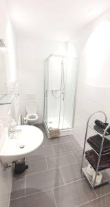 a white bathroom with a shower and a sink at H-Apartment 1 in Triberg