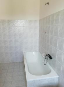 La salle de bains blanche est pourvue d'une baignoire. dans l'établissement Albergo La Torre, à Radicofani