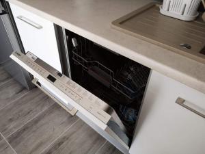 an open dishwasher in a kitchen under a counter at Golden Mazury Apartament in Giżycko