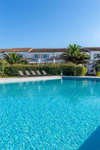 a large blue swimming pool with chairs and a building at Thalacap Île de Ré - Thalasso & Spa in Ars-en-Ré