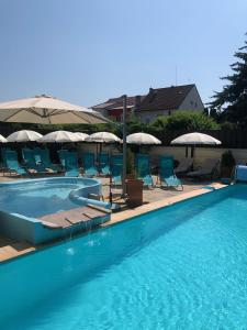 a swimming pool with chairs and umbrellas at Penzion Diana in Piešťany