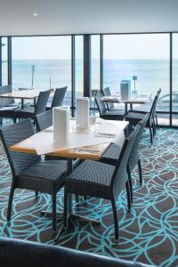 a dining room with tables and chairs and the ocean at Aurora Ozone Hotel Kangaroo Island in Kingscote