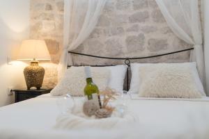 1 dormitorio con 1 cama blanca y 1 botella de vino en Apartment Saint Michael, en Šibenik