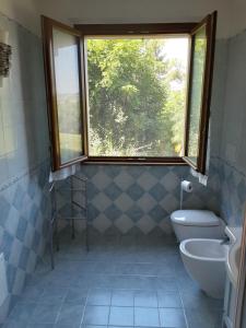 a bathroom with a window and a toilet and a sink at Fonte la Perna in Polverigi