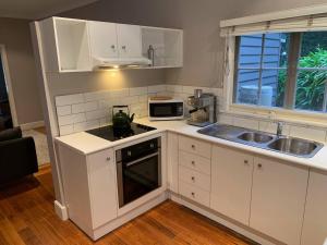 a kitchen with white cabinets and a sink and a microwave at Warby Weekender in Warburton