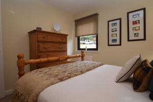 a bedroom with a large bed and a dresser at Dolphin Run in Hunters Quay