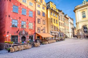 una via cittadina con tavoli e sedie di fronte agli edifici di ApartDirect Gamla Stan a Stoccolma