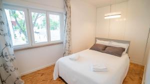 - une chambre avec un lit blanc et une fenêtre dans l'établissement Casual @ 5 de Outubro, à Lisbonne