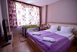 een slaapkamer met een paars bed met handdoeken erop bij City Apartments in Velingrad