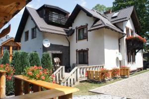 una piccola casa bianca con recinzione e fiori di Willa Góral Goralska Osada Domki Apartamenty Pokoje a Karpacz