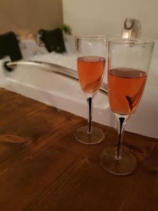 two glasses of wine sitting on a table next to a bath tub at Heaven Guesthouse in Corbeni