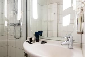 a bathroom with a sink and a mirror and a shower at Ibis Schiphol Amsterdam Airport in Badhoevedorp