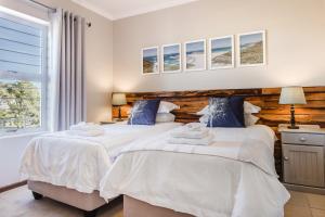 two twin beds in a bedroom with a window at 20 River Club Villas in Plettenberg Bay