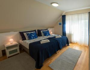 a bedroom with a bed with blue sheets and a window at Airport Apartman in Vecsés