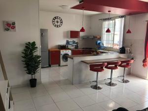cocina con encimera y taburetes rojos en Bel appartement, en Le Moule