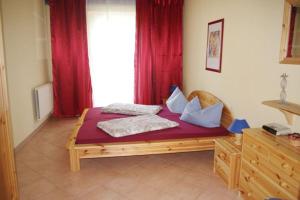 a bed in a room with a window with red curtains at -Waldhaus-Fewo 4 in Granzow