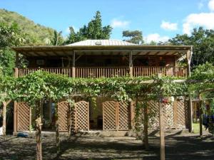 une maison avec une clôture et des arbres devant elle dans l'établissement Domaine de Robinson, à Les Anses-d'Arlet