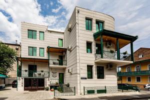 a white building with green windows and balconies at Old Side Corner in Tbilisi City