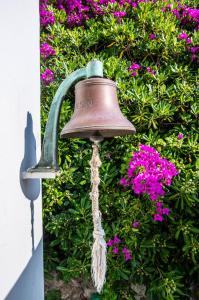 a bell is attached to a bush with pink flowers at Il Carrubo Capri in Anacapri