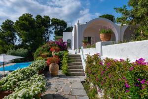 a white house with flowers and a swimming pool at Il Carrubo Capri in Anacapri