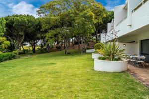 a backyard with a table and chairs and trees at BmyGuest - Quinta do Lago Garden Apartment in Almancil