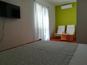 a bedroom with a bed and a tv and two chairs at Salvia Apartments in Trogir