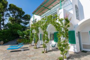 ein weißes Gebäude mit grünen Rollläden und blauen Stühlen in der Unterkunft Il Carrubo Capri in Anacapri