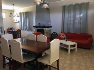 sala de estar con mesa, sillas y sofá rojo en I Colori degli Agrumi Holiday Home, en Floridia