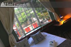 a bedroom with a bed and a large window at Hotel Tazumal House in San Salvador