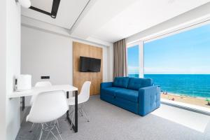 a room with a blue couch and a table with a view of the ocean at Poseidon Deluxe перша лінія з басейном in Odesa