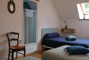 1 dormitorio con 2 camas, silla y espejo en Les Chambres du Moulin, en Susmiou