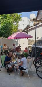 a group of people sitting at a table under an umbrella at Marina's Rooms in Larnaca