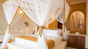1 dormitorio con 2 camas y cortinas blancas en Gold Zanzibar Beach House & Spa, en Kendwa